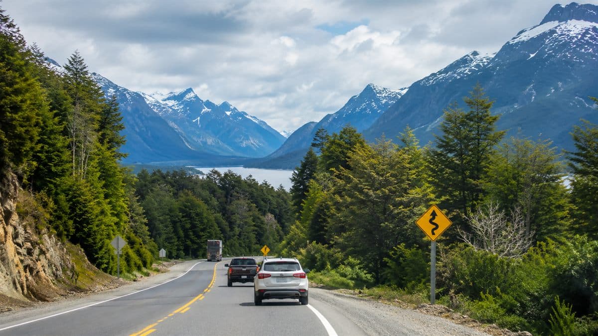 Camino austral en Aysén con vehículos circulando entre bosque, montaña y señalética vial.
