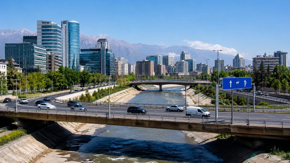 Puente urbano sobre el río Mapocho con vehículos circulando cerca de Costanera Norte y señalética vial.